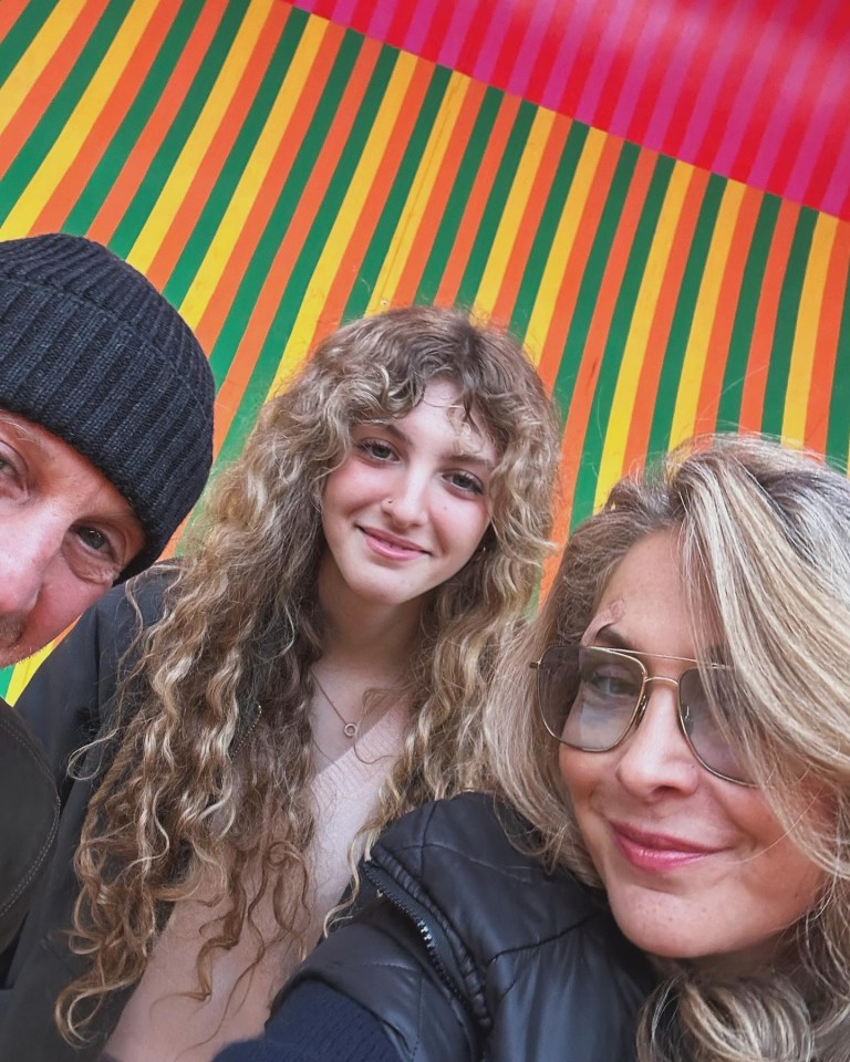 a man and two women pose for a picture in front of a colorful background