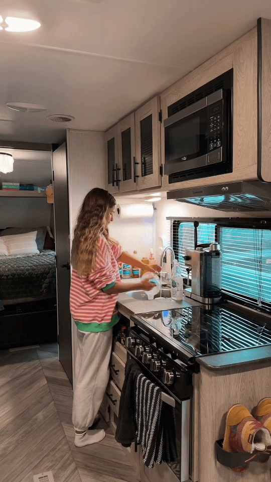 a woman in a striped shirt is washing dishes in a kitchen