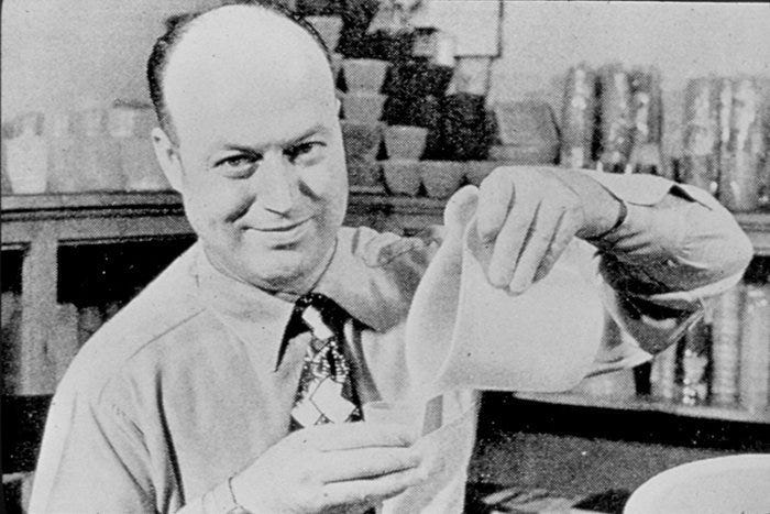 a man in a shirt and tie is pouring something into a glass