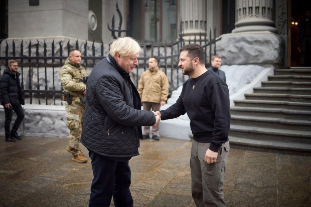 a man in a black jacket shakes hands with another man