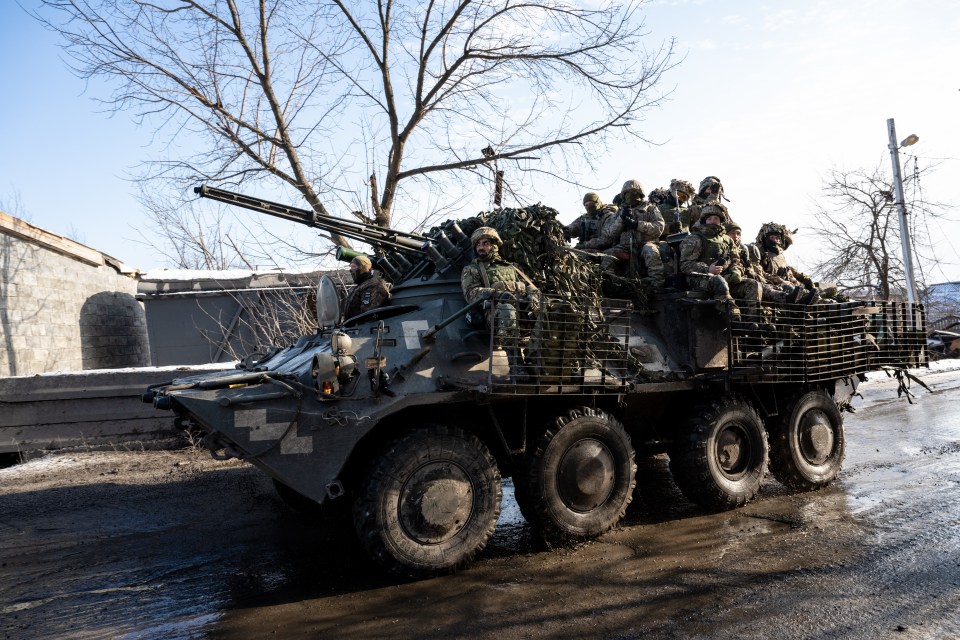 a group of soldiers sit on top of a military vehicle