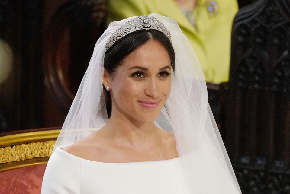 a woman wearing a veil and tiara smiles for the camera