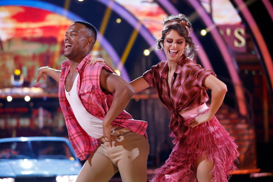 a man and a woman are dancing in front of a sign that says ' s '