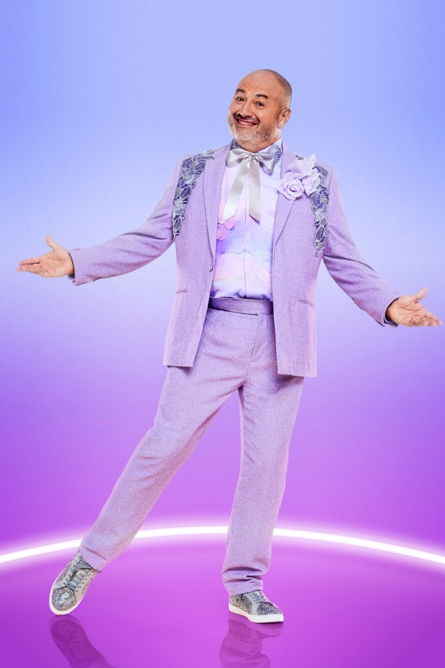 a man in a purple suit is standing with his arms outstretched