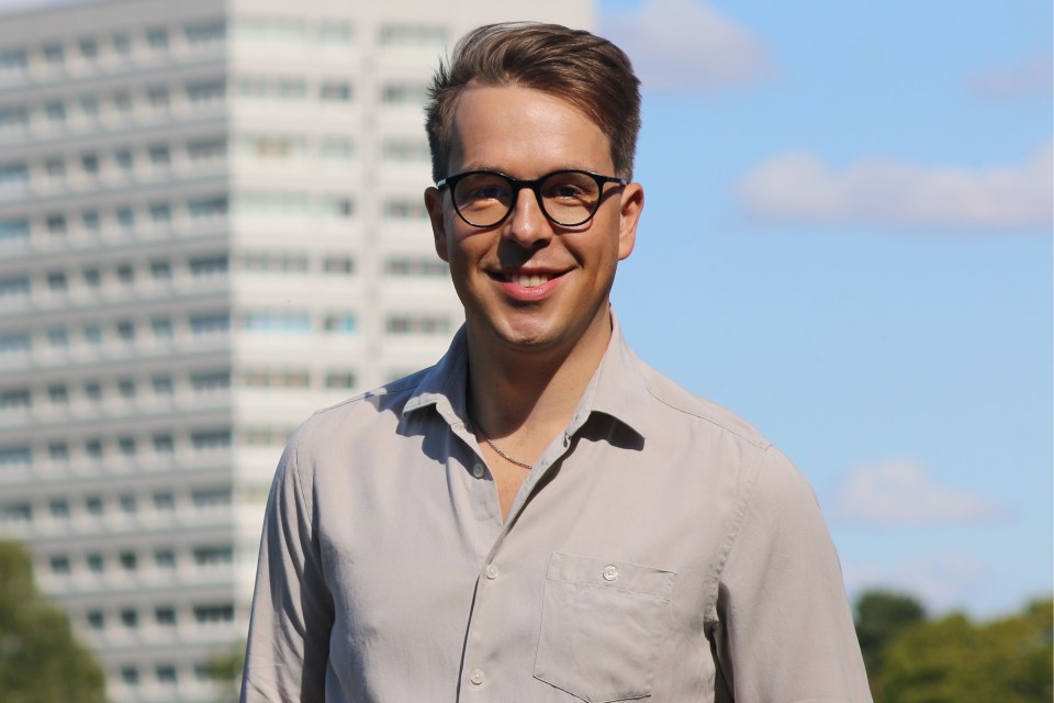 a man wearing glasses stands in front of a building