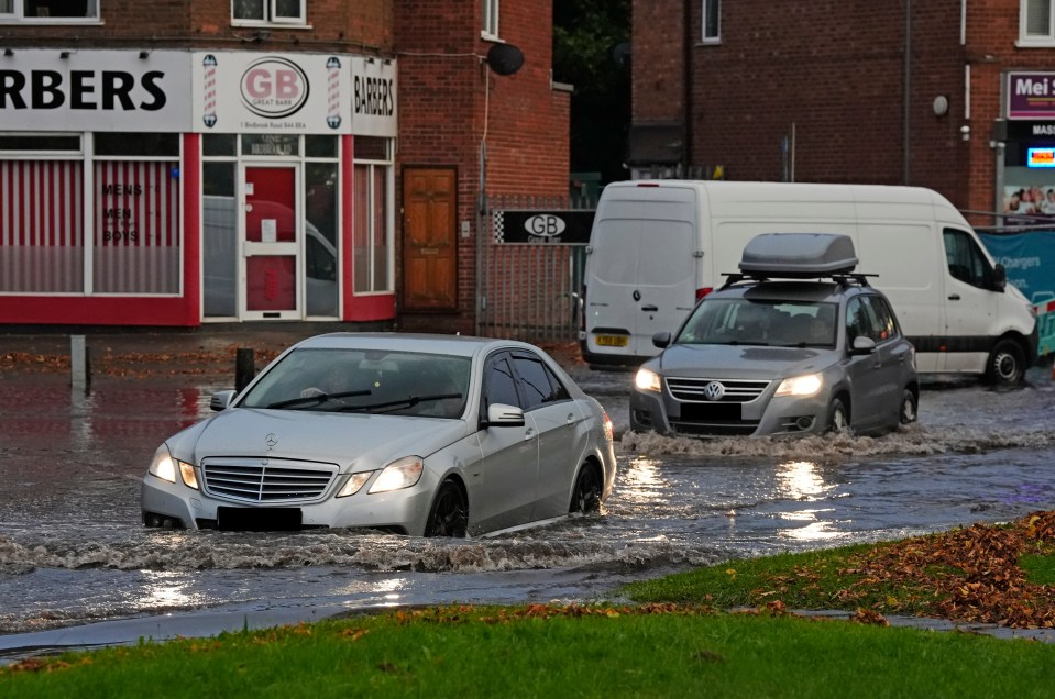 Vehicles drive through flood water in Perry Bar, Birmingham, on Saturday