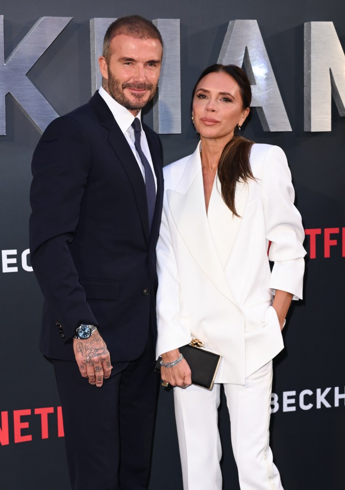 a man in a suit and tie stands next to a woman in a white suit