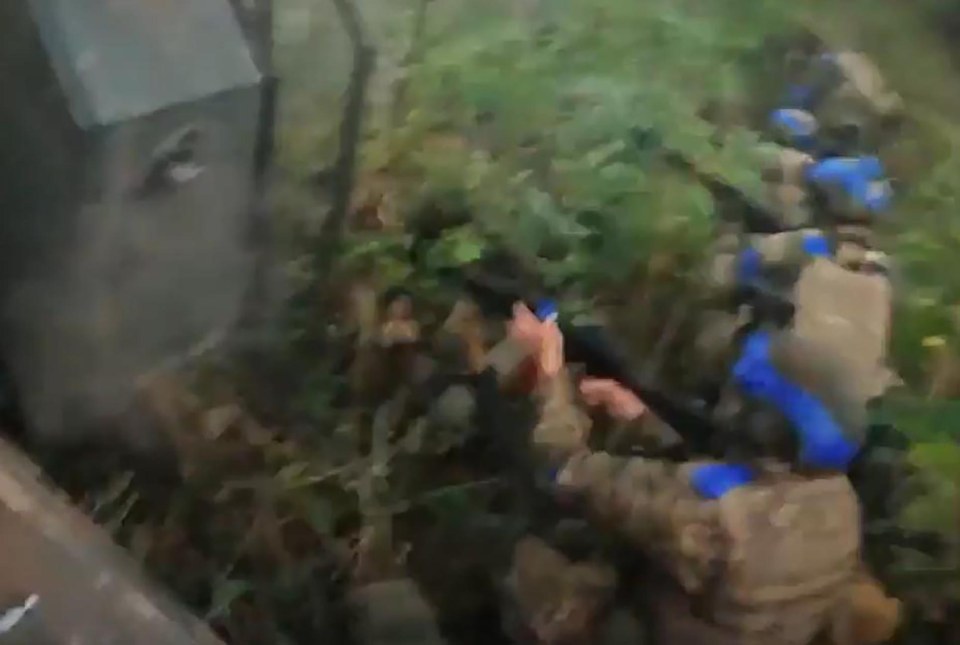 Soldiers are seen diving down into cover in the woods