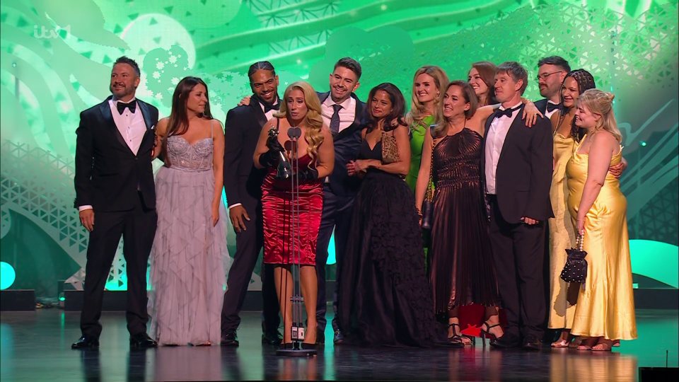 a group of people standing on a stage with a green background