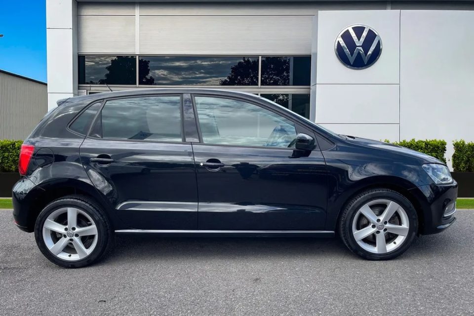 a black volkswagen polo is parked in front of a volkswagen dealership