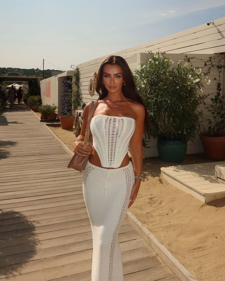 a woman in a white dress stands on a wooden walkway