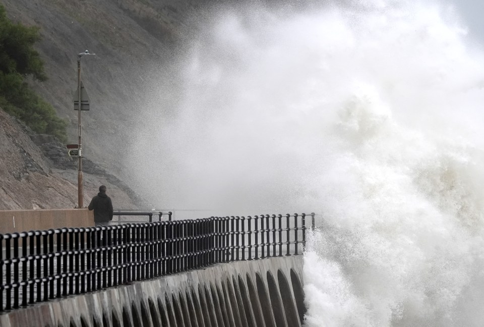 Waves crashing over the promenade during wet and windy weather in Folkestone, Kent today