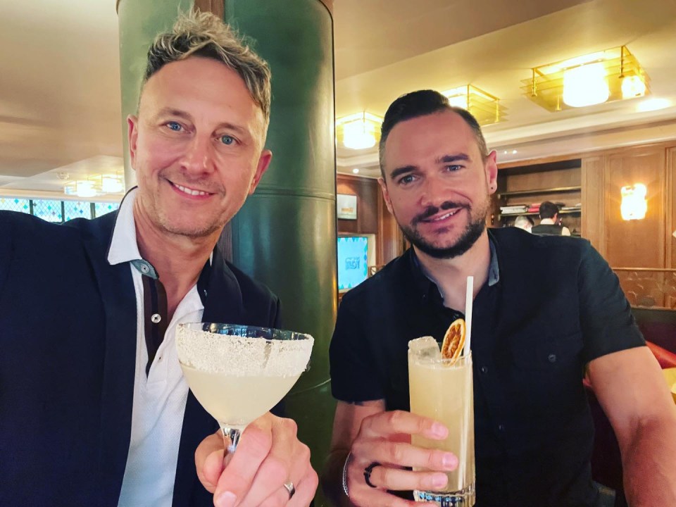 two men are holding up their drinks and one of them has a ring on his finger