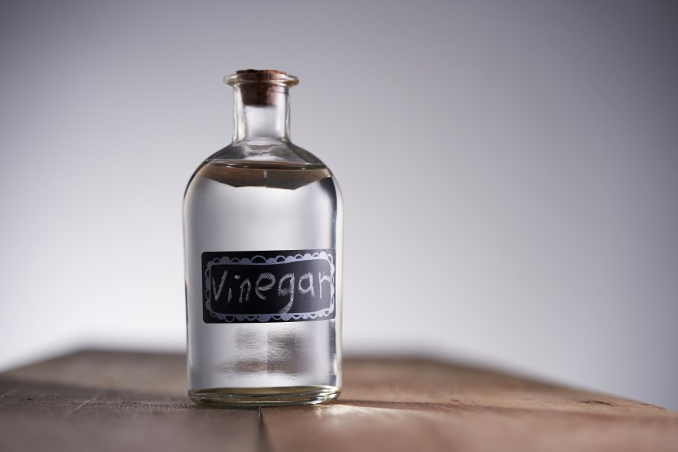 a bottle of vinegar sits on a wooden table