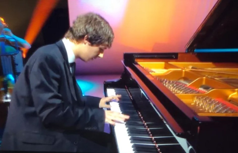 a man in a suit is playing a piano