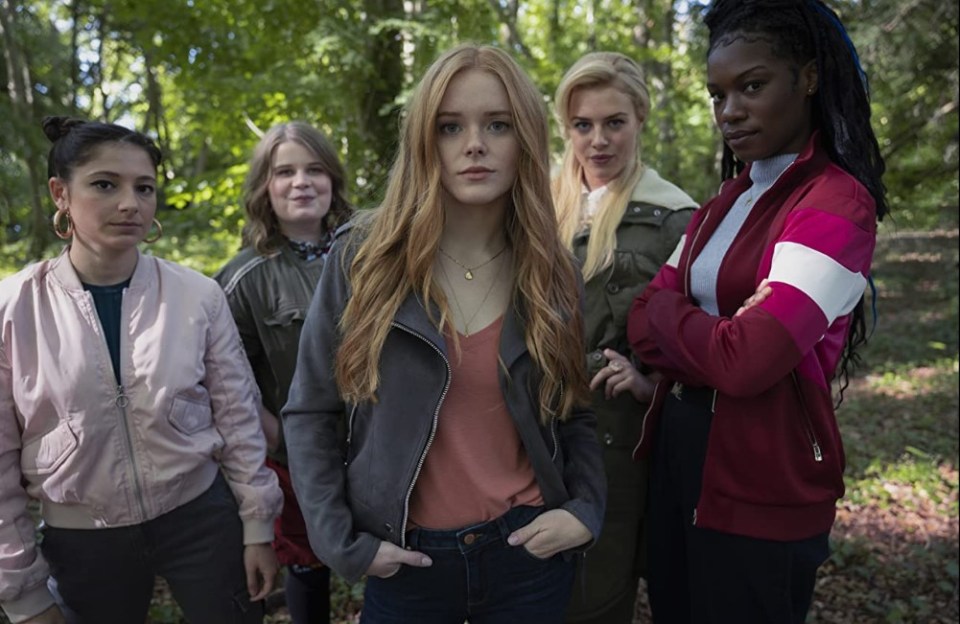 a group of girls are posing for a picture in the woods