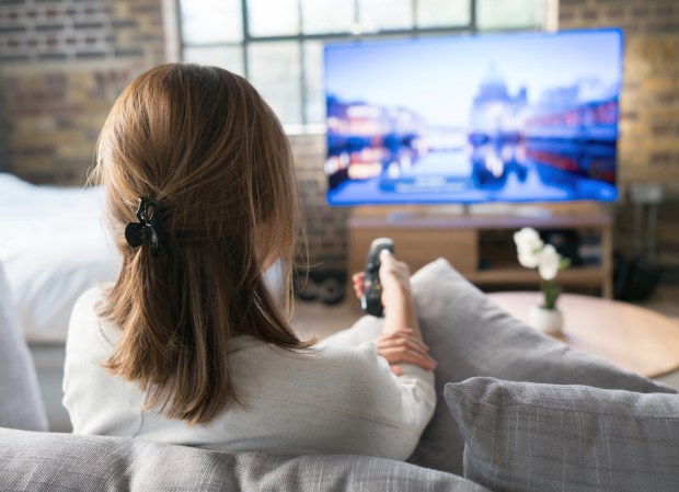 a woman is sitting on a couch watching a tv