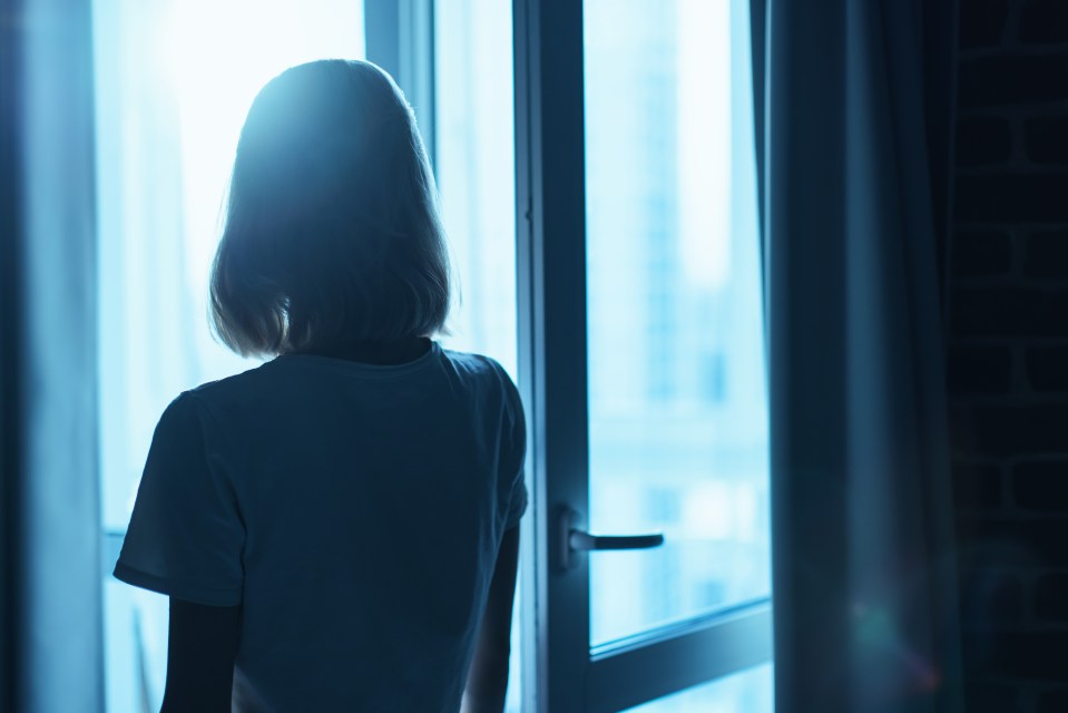 a woman in a white shirt is looking out a window