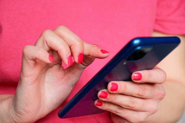 a woman with red nails is using a cell phone