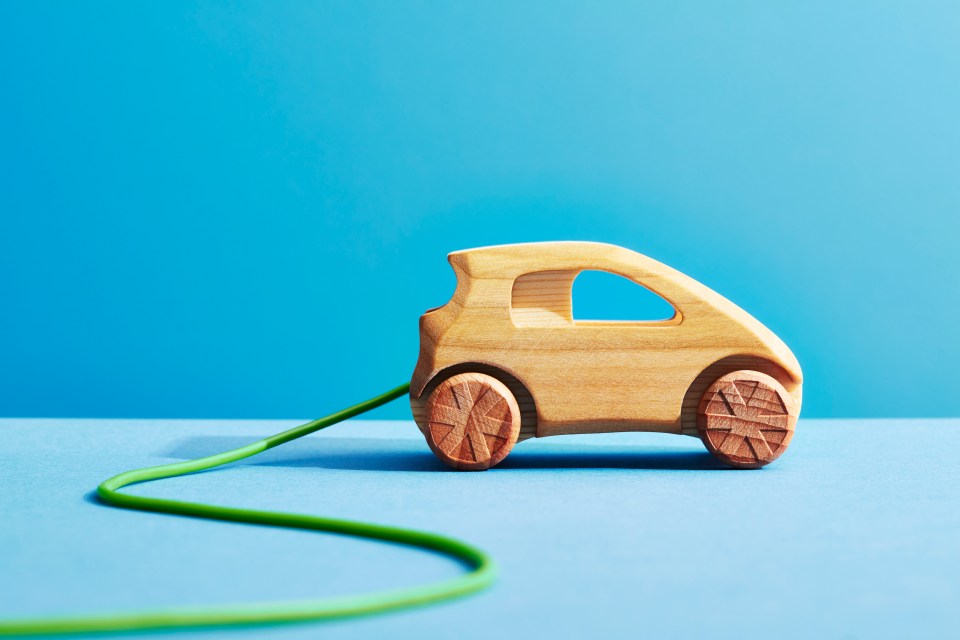 a wooden toy car is plugged into a green cord