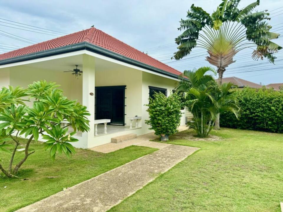 a white house with a red roof and a palm tree in front of it