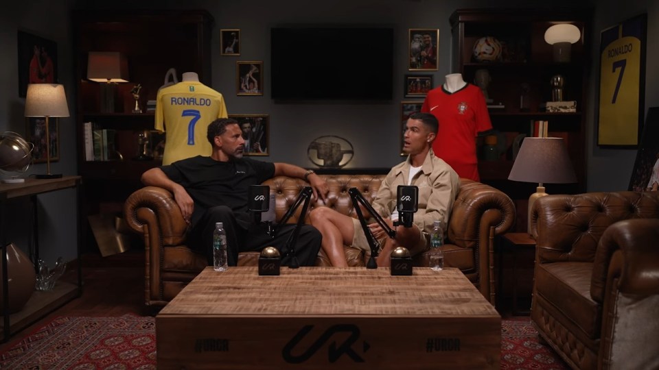 two men sitting on a couch with a ronaldo jersey in the background