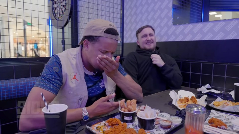 two men sit at a table with a tray of chicken nuggets