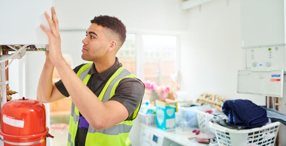 a man in a yellow vest is working on a boiler