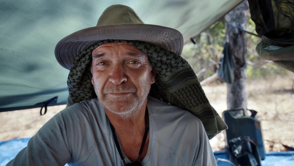 a man wearing a hat and scarf looks at the camera