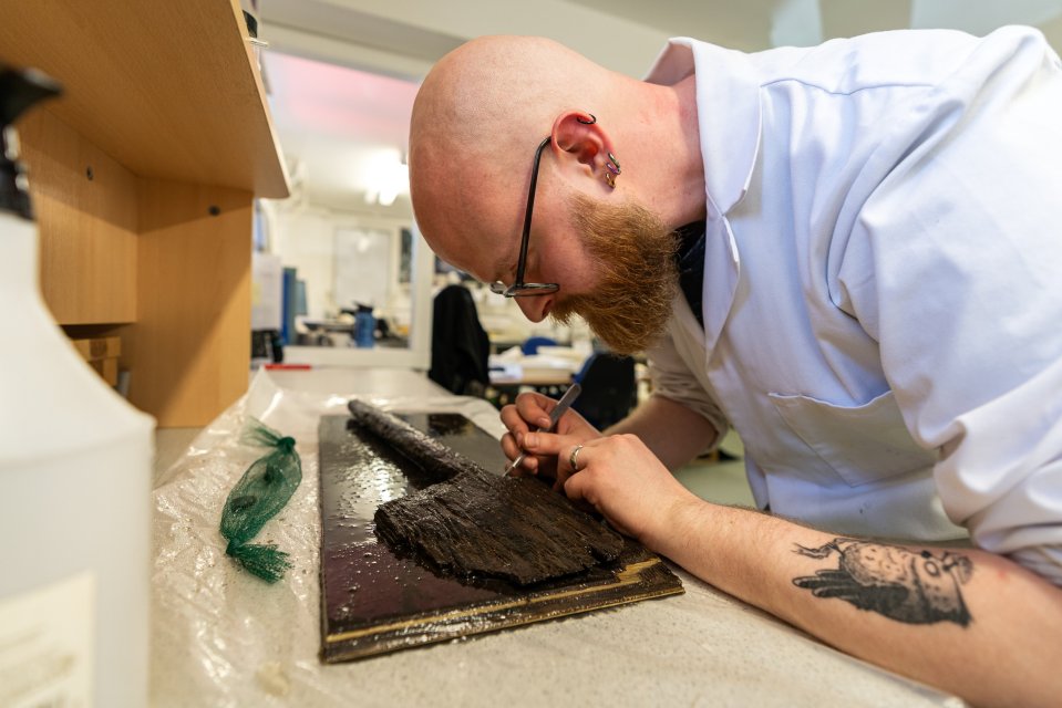 Wessex Archaeology Conservator Thomas Wicks takes a tiny sample of wood from the spade for testing