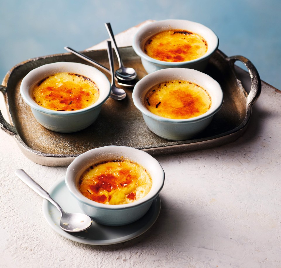 four bowls of custard on a tray with spoons