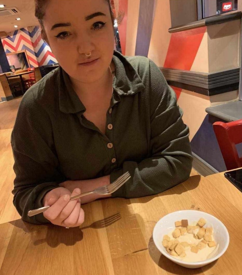 a woman sits at a table with a plate of food and a fork