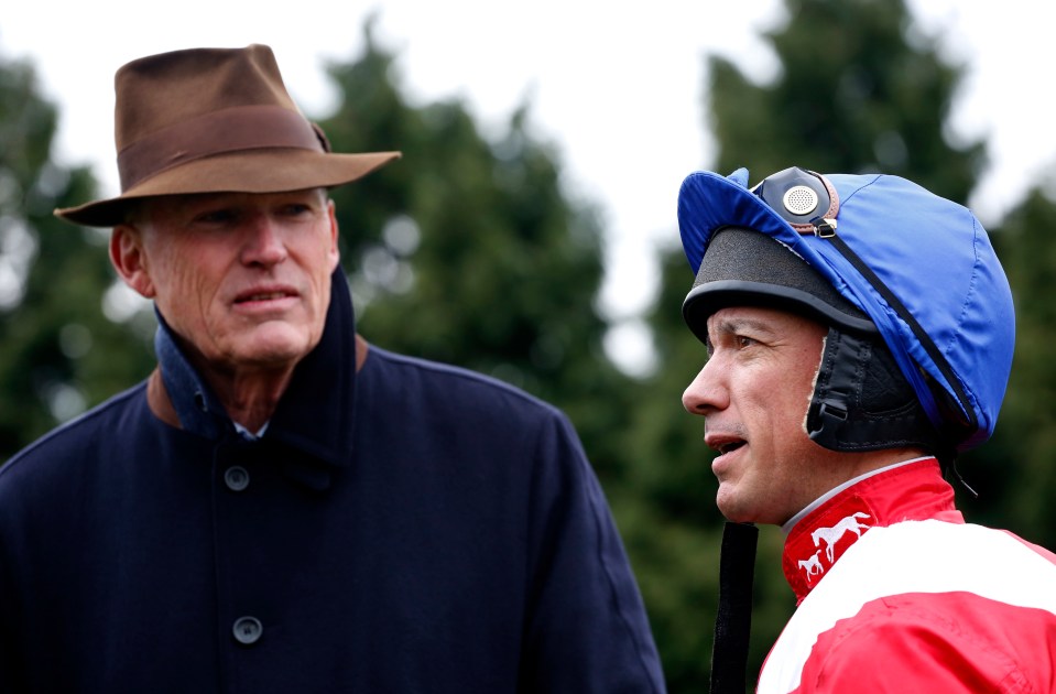 a jockey wearing a blue helmet talks to another man