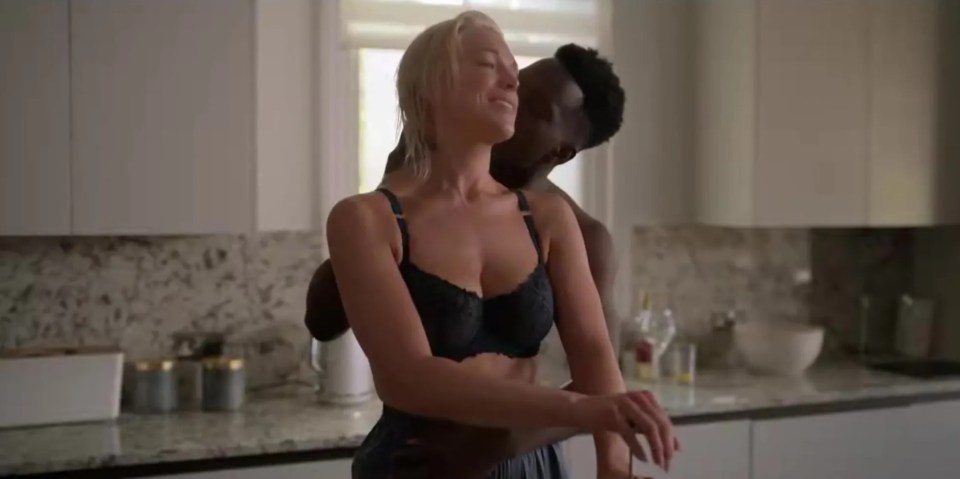 a man is kissing a woman in a bra in a kitchen .