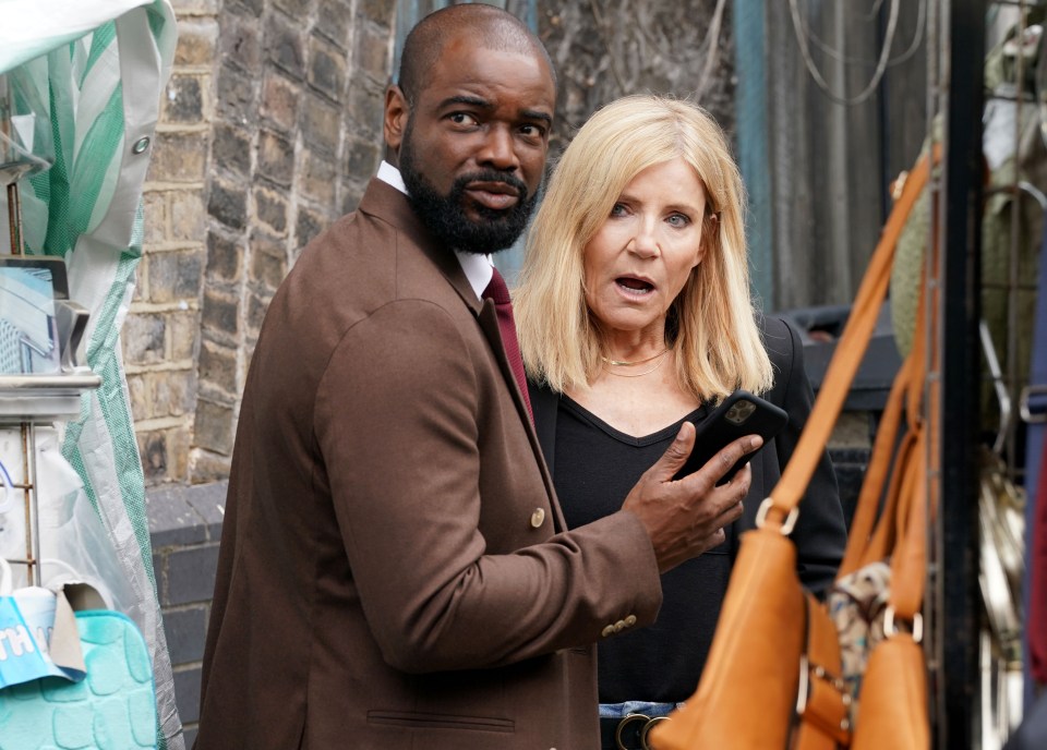 a man and a woman are looking at a cell phone