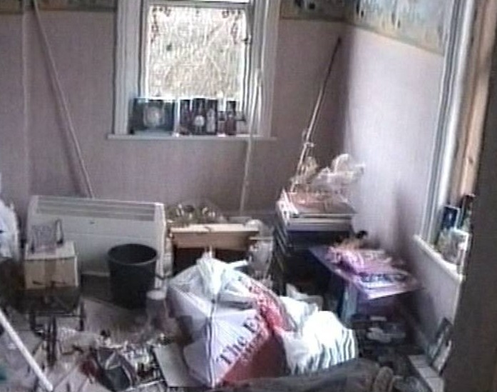 a room with a lot of trash on the floor and a window .