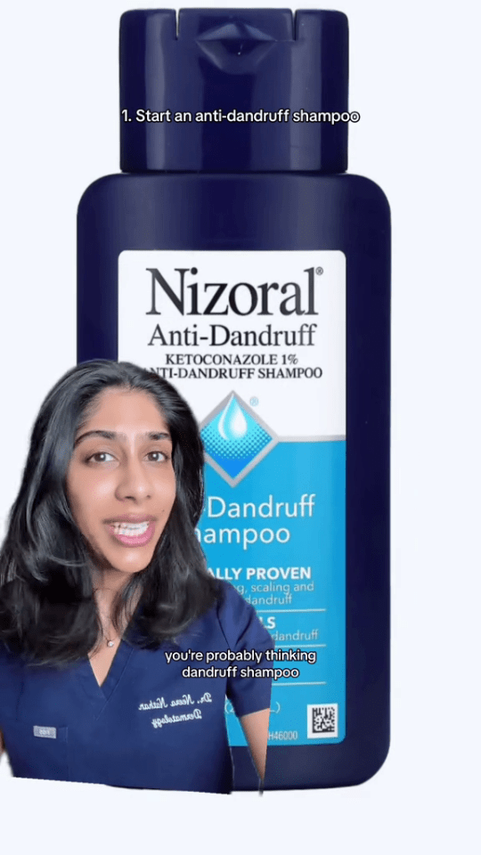 a woman stands in front of a bottle of nizoral anti dandruff shampoo