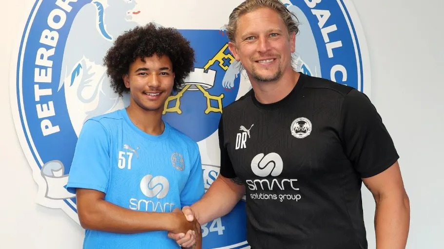 two men shaking hands in front of a peterborough fc logo