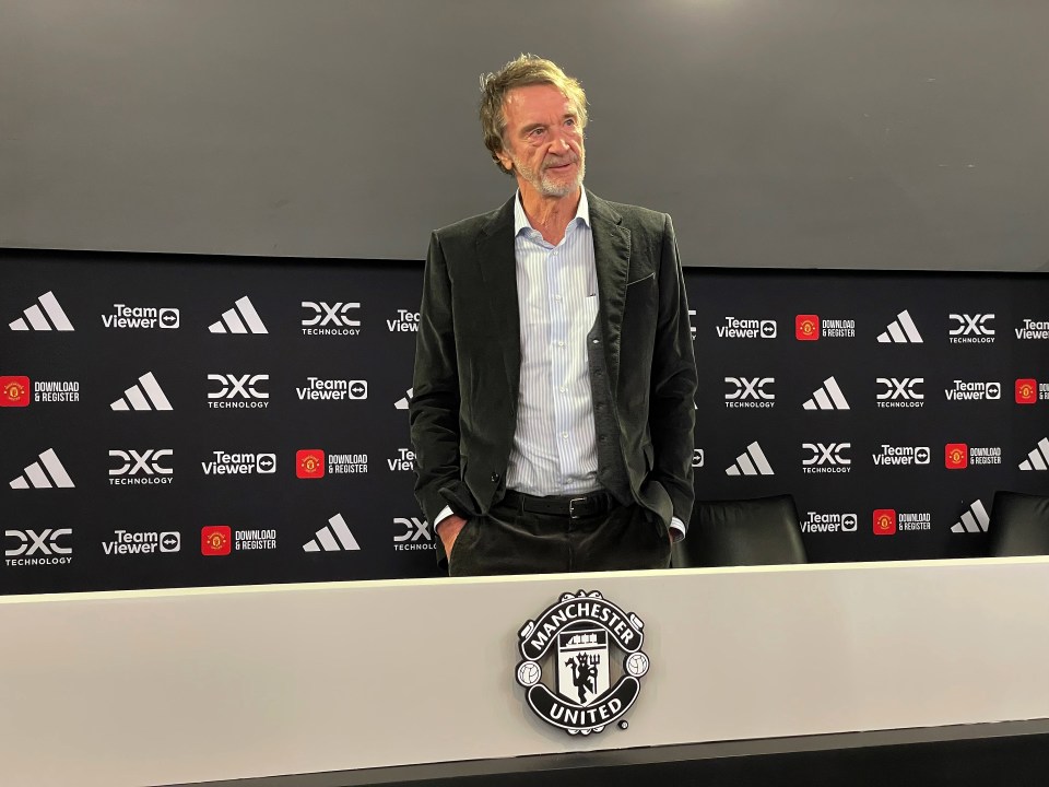 a man stands in front of a manchester united sign