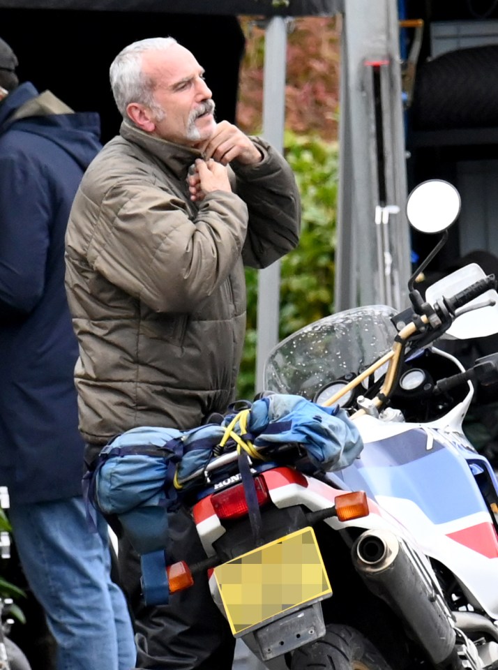 a man standing next to a suzuki motorcycle