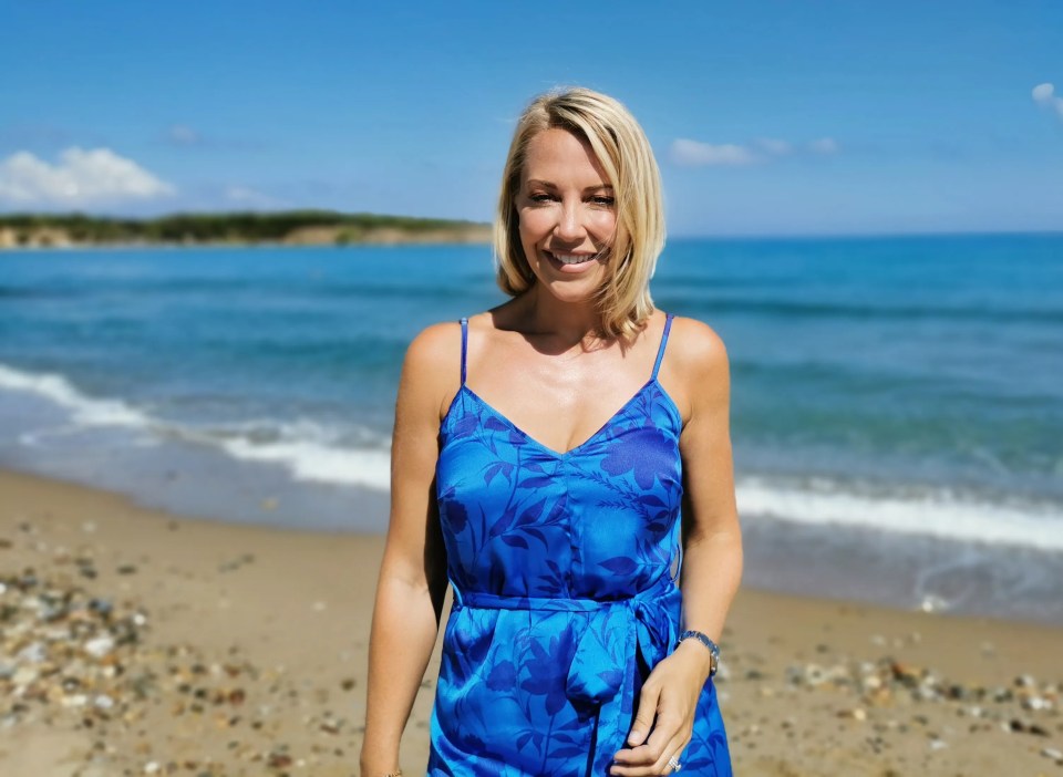 a woman in a blue dress stands on a beach