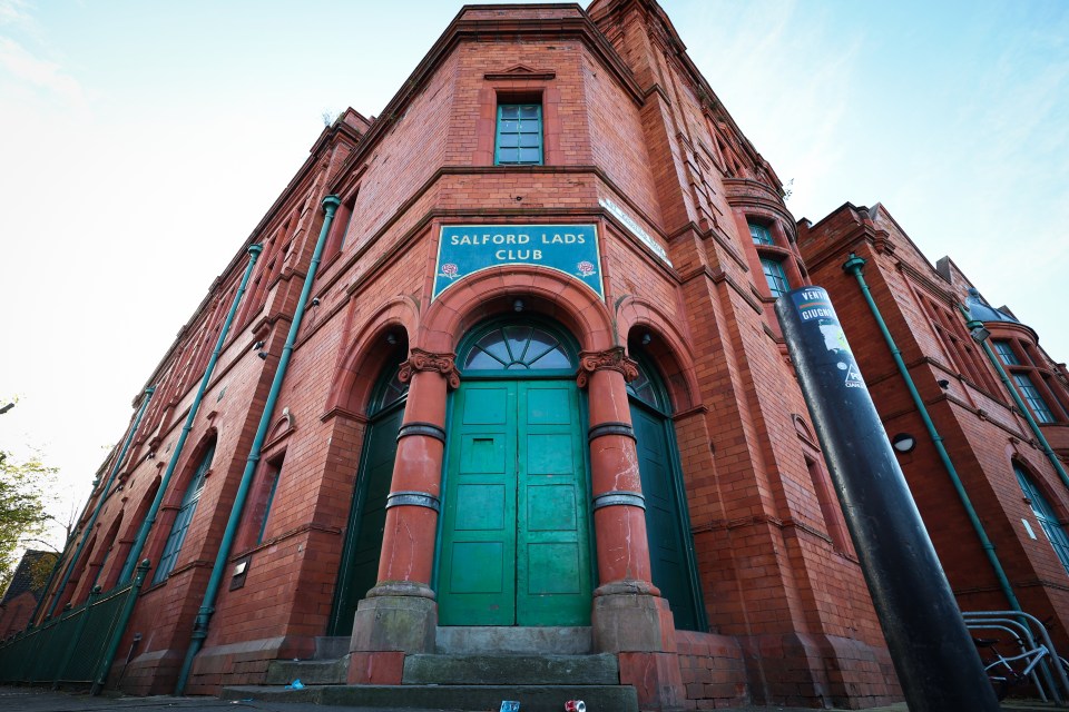 a red brick building with a green door that says salford lads club