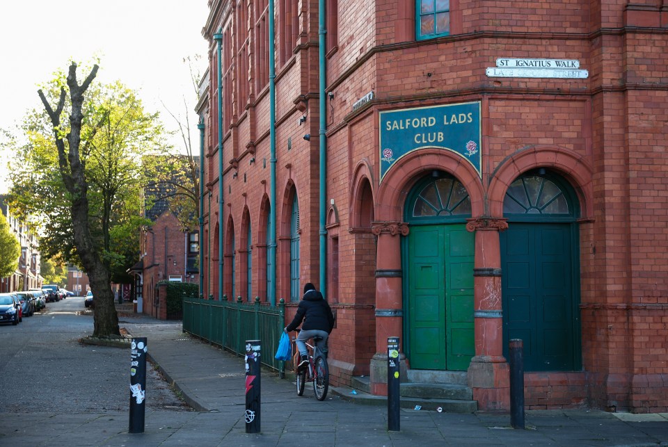 a person riding a bike in front of a building that says salford lads club