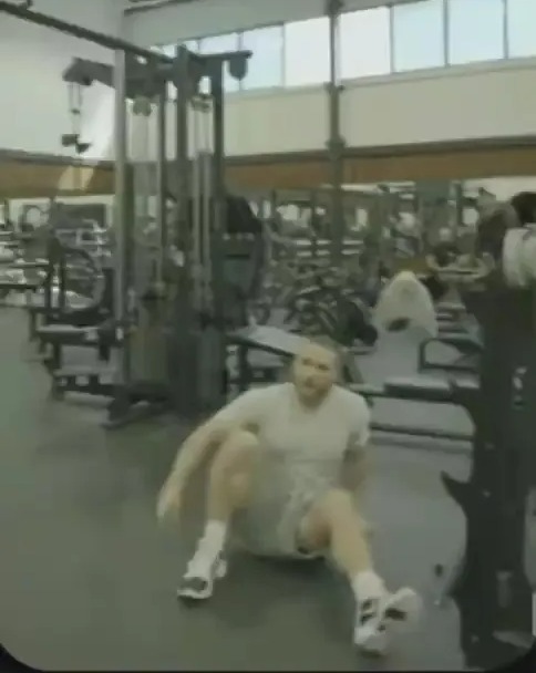 a man is sitting on the floor in a gym .