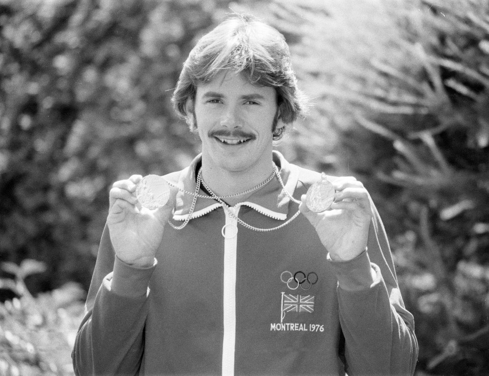 a man in a montreal 1976 jacket holds up two medals