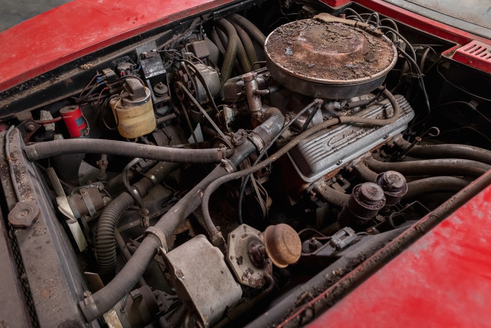 a red car with a dirty engine that says chevrolet on it