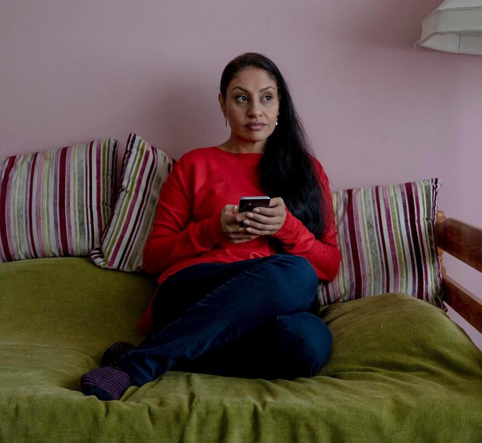 a woman sits on a green couch holding a cell phone