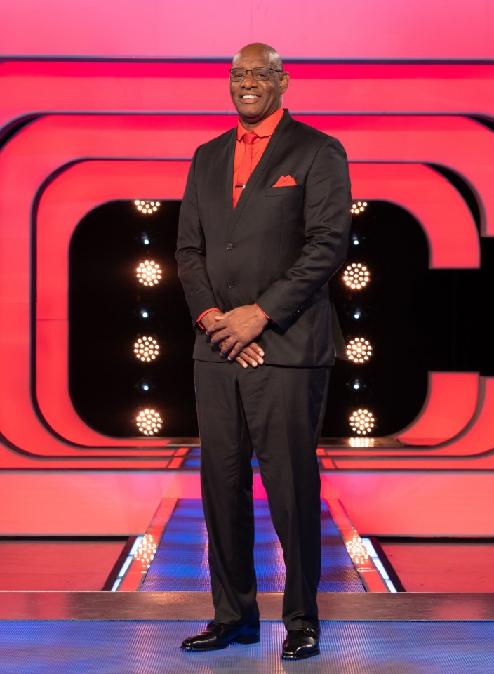 a man in a suit and red shirt stands on a stage