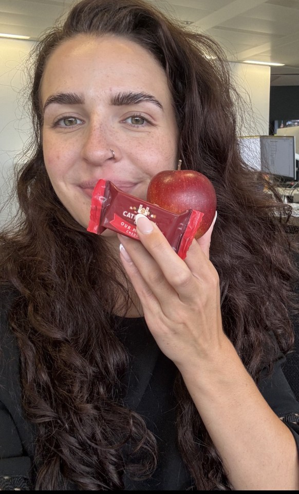 a woman holding an apple and a candy bar that says ' castello ' on it