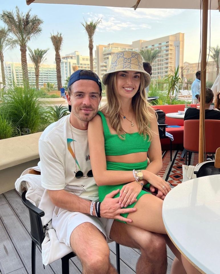 a man wearing a gucci hat sits next to a woman in a green bikini